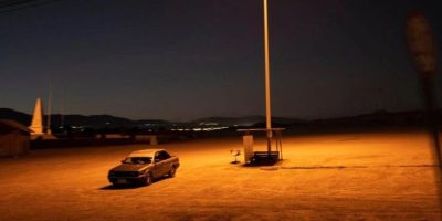 Driver sitting alone in a parked car in an empty lot, taking a moment to relax