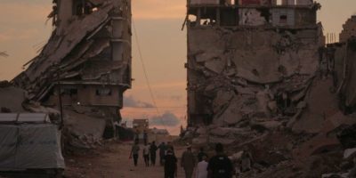 Palestinians walk past buildings destroyed by Israeli military strikes in Gaza City on Oct. 6, 2026.