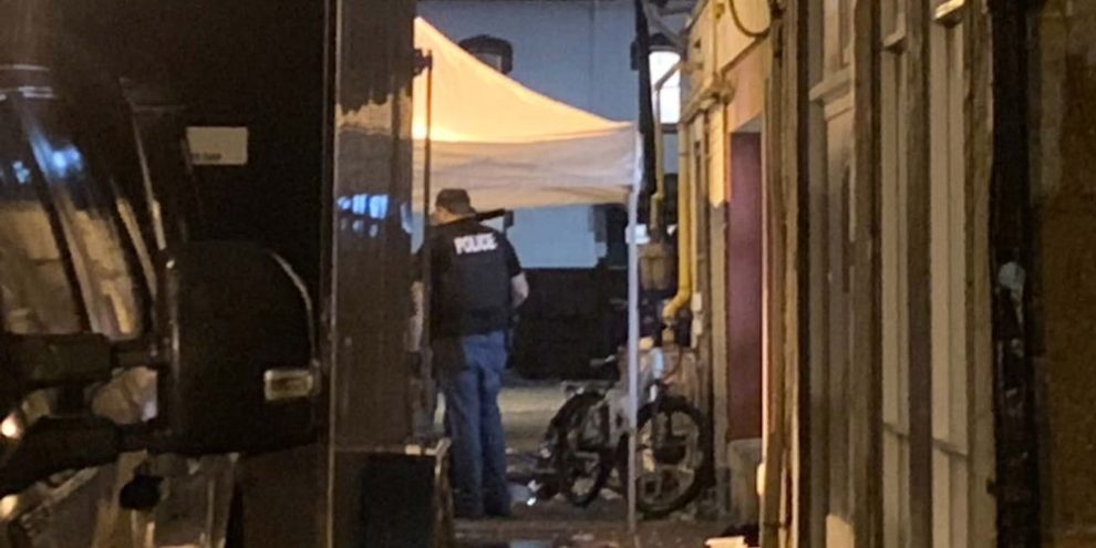 Barrie Police officers working under a white tent in an alley off Maple Avenue following a drug-related warrant.